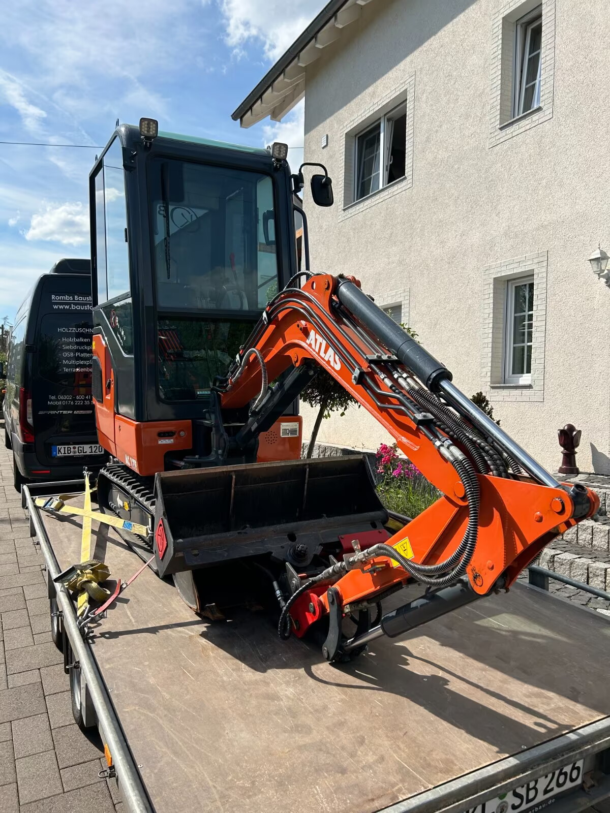 Minibagger mieten, kompakte Bauweise, orangefarbene Lackierung, montiert auf Anhänger